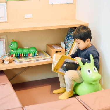 キッズスペースで絵本を読む男の子｜院内には子どもが楽しく待てるスペースを完備