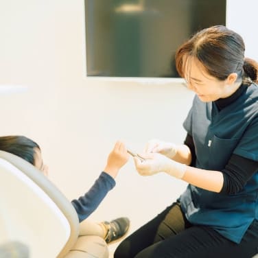 子どもの患者と会話する女性歯科医｜お子様の歯科治療はトレーニングからスタート